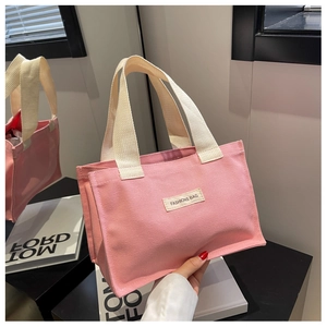 Gros plan détaillé du sac cabas en toile rose avec étiquette FASHIONS BAG et anses crème