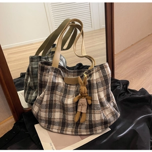 Detail of plaid tote bag featuring leather handles and a cute rabbit plush pendant accessory