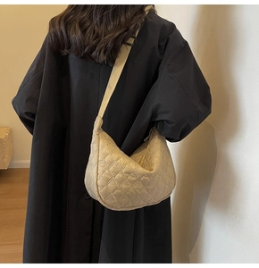 Detailed close-up of beige quilted hobo bag with adjustable strap and diamond pattern