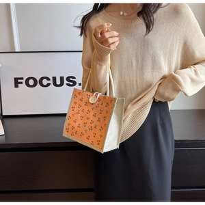 Detail of orange corduroy tote bag with blue cherry pattern and braided rope handles