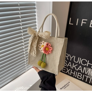 Close-up of beige linen handbag featuring handmade crochet floral decor and lace bow