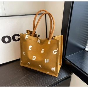 Close-up of yellow canvas tote bag with white lettering on black wood table
