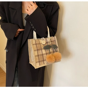 Detail of plaid tote bag with rope handles, wooden button, and plush cherry charm