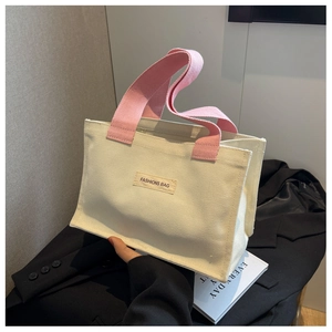 Gros plan du sac fourre-tout en toile crème avec anses roses et détail d'étiquette mode