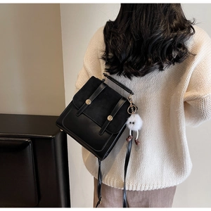 Close-up of vintage black leather backpack with gold buckle on a model wearing a knit sweater