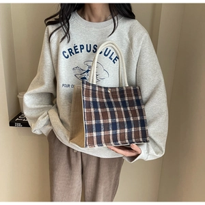 Détail d'un cabas à carreaux vintage avec poignées en corde et boucle métallique dorée