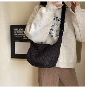Close-up of a black quilted half-moon crossbody bag featuring classic rhombic stitching details
