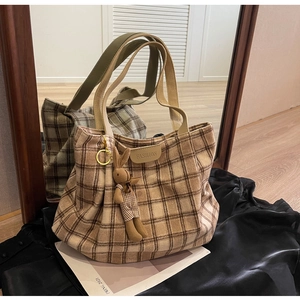 Detail of checkered woolen tote bag with leather fashion tag and plush rabbit charm