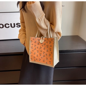 Detail of corduroy handbag with cherry pattern, wooden button, and cotton rope handle