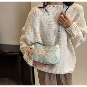 Détail du sac bandoulière en cuir bleu clair avec broderie papillon rose élégante
