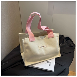 Détail du sac cabas en toile avec anses roses et étiquette mode sur un blazer noir