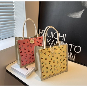 Detailed shot of corduroy tote bags with cherry prints and woven rope handles
