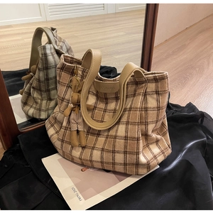 Detailed close-up of brown checkered wool tote bag with leather logo and rabbit charm