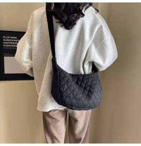 Lifestyle view of a black quilted crescent crossbody bag with adjustable wide strap