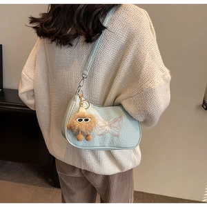 Détail du sac à bandoulière vert menthe à motif crocodile avec broderie papillon et breloque