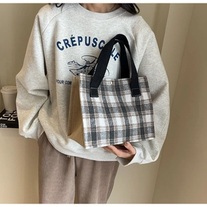 Détail du fermoir en métal et de la couture en lin à carreaux sur le sac fourre-tout