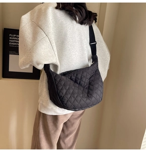 Quilted black nylon crescent bag shown worn as a crossbody on a female model