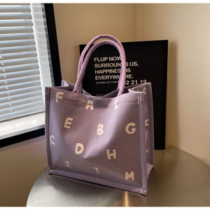 Detailed view of the purple canvas tote bag with thick texture and white typography