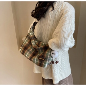 Détail d'un sac bandoulière en laine à carreaux avec breloque peluche blanche