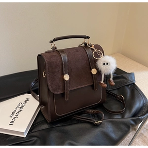 Detailed view of vintage brown leather backpack with metal buckles and plush charm