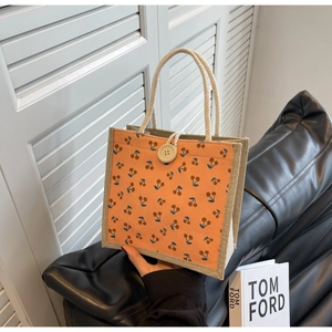 Detailed shot of orange cherry print corduroy tote with linen sides and rope handles