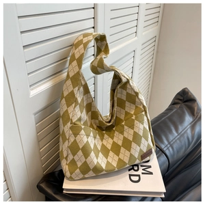 Detail of green argyle canvas hobo bag with leather fashion tag on Tom Ford book