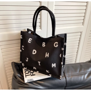 Detail of black canvas tote bag with bold white letter print and rope handles