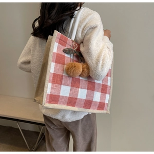 Detailed shot of waffle tote bag featuring red plaid, jute sides and a cherry charm