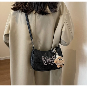 Détail du sac à bandoulière nœud noir avec broderie papillon et pendentif en peluche