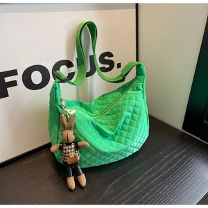 Détail du sac hobo matelassé vert vif avec breloque lapin sur fond en bois sombre