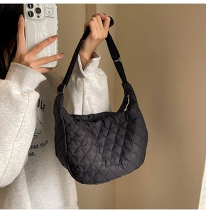 Macro detail of black quilted nylon dumpling bag showing soft puffer texture and strap
