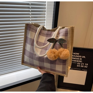 Detail of purple checkered linen tote bag with cream rope handle and cherry fur charm