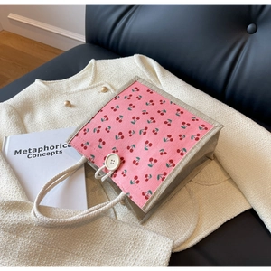Close-up of linen tote bag featuring pink cherry patterns and thick white cotton rope handles