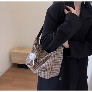 Détail du sac hobo à carreaux vintage avec breloque en peluche porté par un mannequin