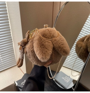 Detail of plush brown bag with cute rabbit ears, gold chain, and teddy bear charm