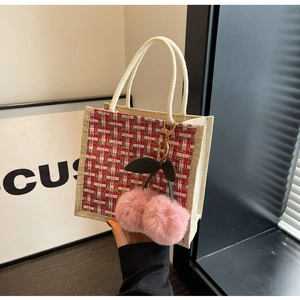 Detailed view of red and white plaid tweed tote bag with a plush cherry charm
