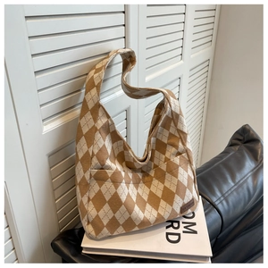 Close-up of diamond pattern knit tote bag with fashion leather tag on a sofa