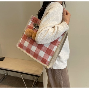 Close-up of red and white waffle plaid tote bag with cute brown plush cherry pendant