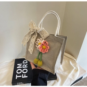 Close-up of beige woven bento bag featuring delicate lace bow and floral decorations