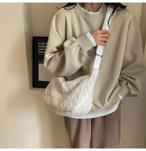 Close-up of white quilted crescent bag showing soft padding and adjustable strap