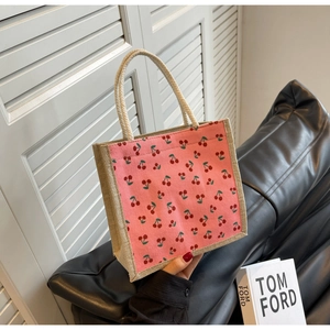 Detailed shot of pink corduroy handbag with cherry print and natural hemp handles