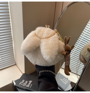 Detail of plush bunny ear crossbody bag with gold chain strap and knitted rabbit charm