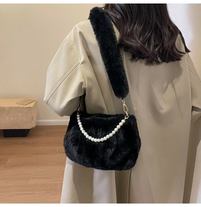 Detail of plush black shoulder bag with faux pearl strap on model in beige trench coat