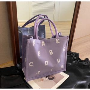 Detail of lavender canvas tote with white letter prints and reinforced handle design