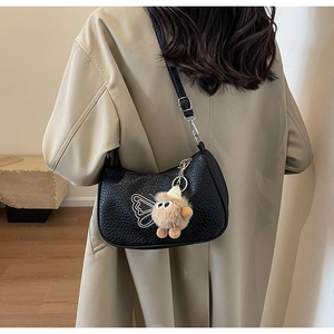 Vue latérale du sac à bandoulière en cuir noir avec broderie et charm en peluche