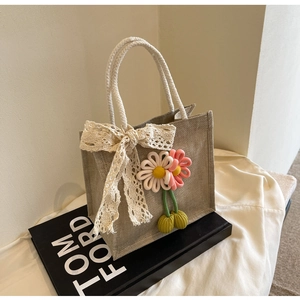 Detail of hand-woven lunch bag featuring beige lace bow and pink crochet flowers decoration