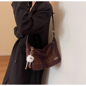 Détail d'un sac en laine à carreaux rétro avec étiquette mode et pendentif monstre
