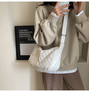 Detailed view of white quilted half-moon crossbody bag with soft padded nylon texture