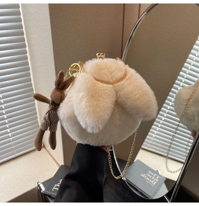 Detail of soft cream plush rabbit bag with gold metal chain and brown bunny charm