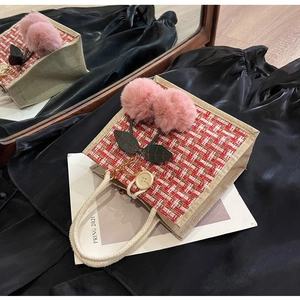 Detail of red tweed woven handbag with cherry pompoms and white rope handle